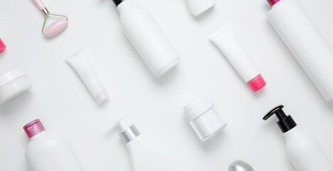 Cosmetic beauty products on white background. Bottles and tubes with branding mock up. Skin care and beauty concept. Top view, flat lay, copy space, banner