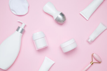 Cosmetic beauty products on pink background. Bottles and tubes with branding mock up. Skin care and beauty concept. Top view, flat lay