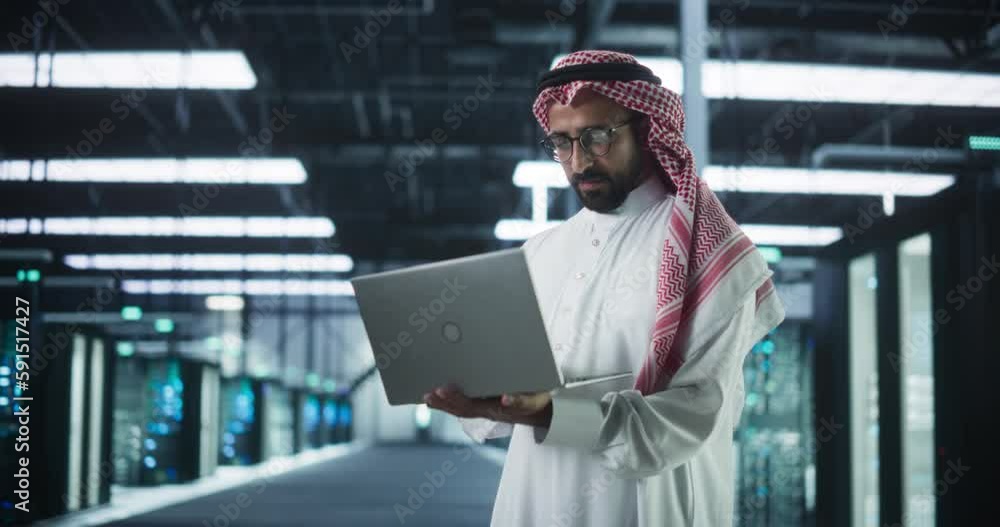 Leinwandbilder portrait of a middle eastern it system engineer wearing traditional white robe, using laptop compute