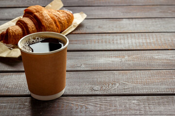 One paper cup of coffee with croissant. Takeaway coffee with snack