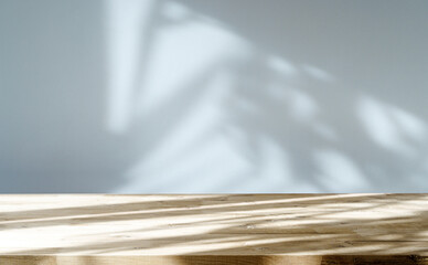 Table shadow background. Wooden table and white empty wall with plant shadows. - obrazy, fototapety, plakaty