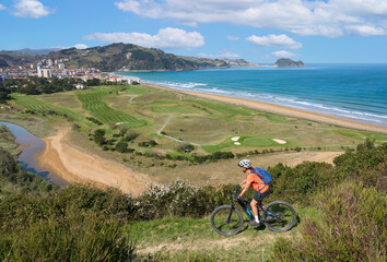nice senior woman cycling with her electric mountain bike in the hills above Zarautz, Basque...