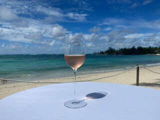 Glass of rose wine on beach against backdrop of sea or ocean