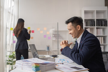 The couple of business employee working in the office with laptop and holding the coffee cup, happy, 