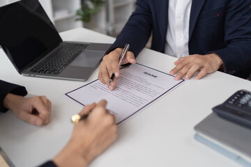 Obraz premium Happy young Asian businessman and woman shaking hands to congratulate successful collaboration on business deal with documents and laptop on table in the office.