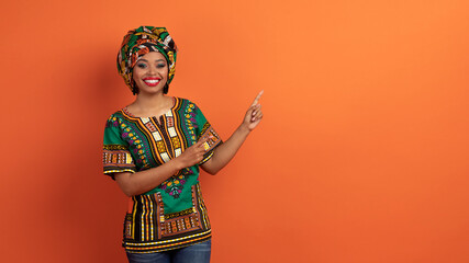 Obraz premium Pretty black woman in african costume pointing at free space