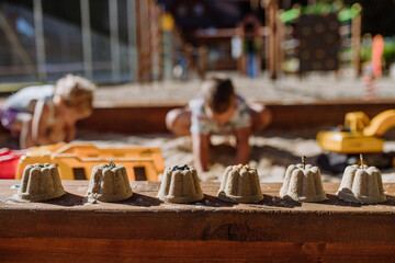 Close up of sands cake made by children in background.
