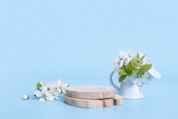 Wooden podium or pedestal for cosmetics with sprigs of spring flowers. Spring mockup podium background