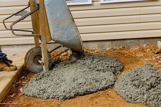 Construction worker pours cement from wheelbarrow to create concrete sidewalk that will be used for future