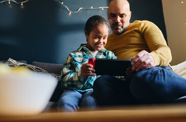 Father supporting son with Down syndrome playing computer game