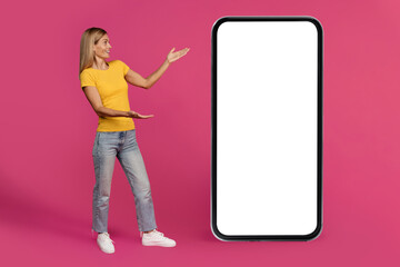 App recommend, presentation. Shocked smiling mature european woman pointing hands at huge smartphone