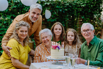 Multi-generation family on outdoor summer garden party, celebrating birthday