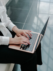 Woman holding a laptop in her hands and typing on the keyboard, close-up