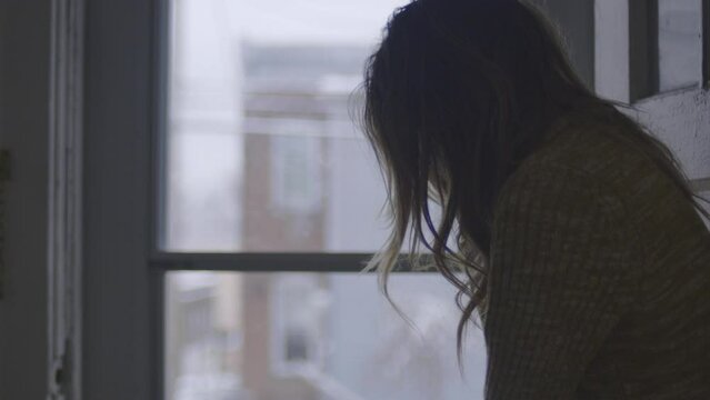 A disheveled woman slowly raises her head while overcome by depression