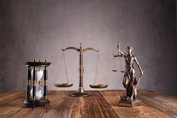 Law symbols composition. Gavel, scale and Themis sculpture on the rustic wooden desk. Gray...
