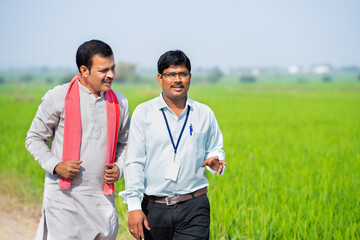 Banking officer with Village farmer discussing by looking around farmland - concept of information...