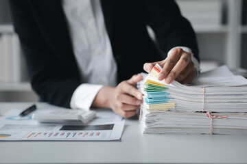 Businessman looking through stacks of papers on desk, corporate financial papers, monthly financial summary papers. Concept of document management in the organization.