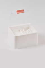 White new plastic organizer for cosmetic products filled with cotton sticks and pads isolated on white background