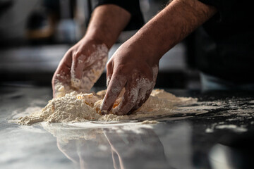 Making dough by male hands on a dark background. home cooking concept