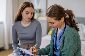 Teenage girl having stomach ache, young doctor examining her.