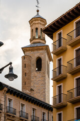 Pamplona, Navarra, SPAIN. The beautiful streets of the city of Pamplona. Beautifully coloured buildings with flowers of different colours, hanging from the balconies. Church tower in backgroundPamplon