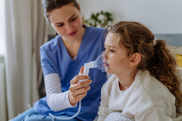 Little girl with inhaler in hospital room, nurse chcecking her.