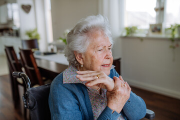 Portrait of senior woman on wheelchair with pain in her hand.