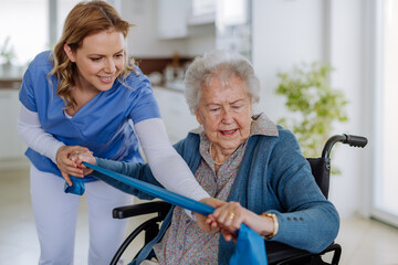 Nurse exercising with senior woman at her home, concept of healthcare and rehabilitation.