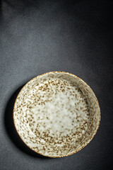minimalist handmade ceramic plate on a black concrete table, top view