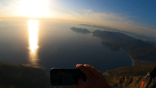 paragliding point of view in Oludeniz. paraglider flying over the sea on sunset, holds phone in his hand and photographs, shoots fotos. panoramic view from gopro. High quality FullHD footage