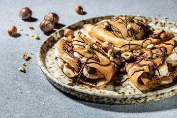 Homemade thin crepes with chocolate spread, banana and hazelnuts. breakfast or dessert. banner, menu, recipe place for text, top view