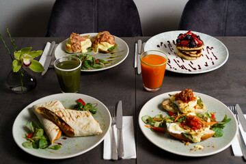 Brunch with four plates of meals - egg toast, burrito, american pancake and juices