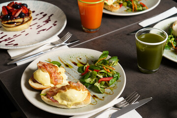 Toast with Egg, Cheese and Bacon on top and Salad on the side at the table