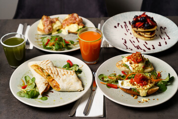 Brunch with four plates of meals - egg toast, burrito, american pancake and juices