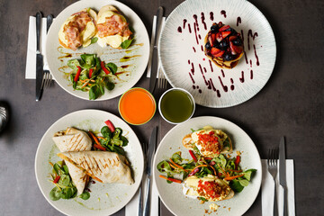 Brunch with four plates of meals - egg toast, burrito, american pancake and juices