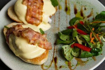 Close up of Toast with Egg, Cheese and Bacon on top. Salad on the side