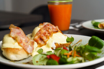 Toast with Egg, Cheese and Bacon on top and Salad on the side at the table