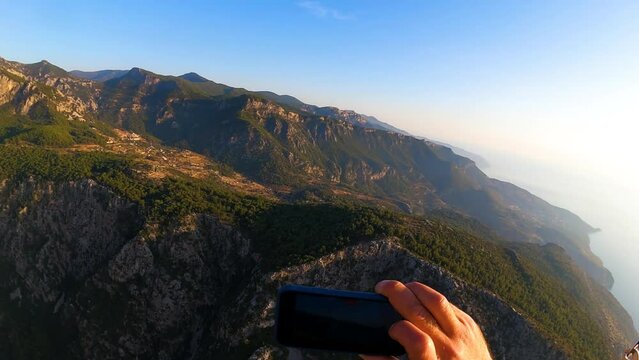 paragliding point of view in Oludeniz. paraglider flying in the mountains on sunset, holds phone in his hand and shoots a video. panoramic from gopro from right to left. High quality FullHD footage