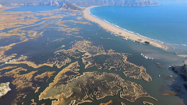 Drone video of İztuzu Beach in Dalyan, Muğla, featuring sandy coastline, azure waters, mountains, and a perfect vacation destination.