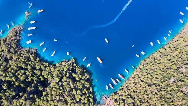 Aerial view of sailboats and swimmers enjoying the beautiful Kleopatra Hamamı Cove, located between G&ouml;cek and Dalaman, Turkey, known for its crystal-clear waters and ancient ruins.