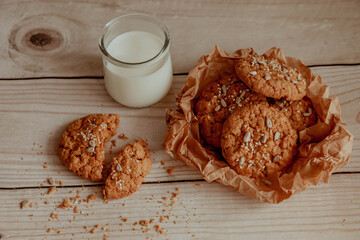 Oatmeal cookies with milk on light background with crumbs
