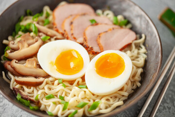 Japanese ramen noodles with pork slice, shiitake mushrooms and egg in a black bowl