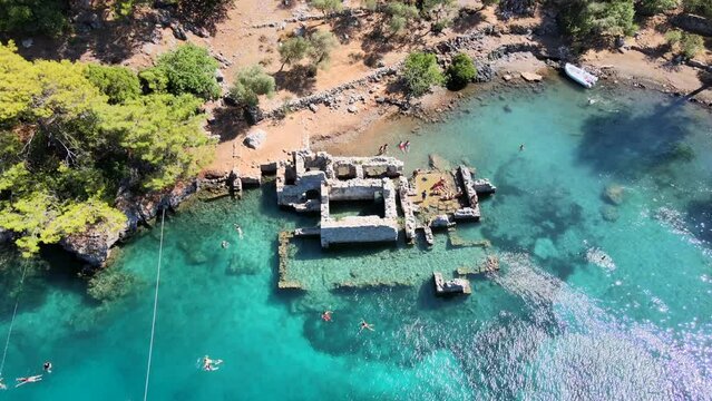 Aerial view of sailboats and swimmers enjoying the beautiful Kleopatra Hamamı Cove, located between G&ouml;cek and Dalaman, Turkey, known for its crystal-clear waters and ancient ruins.
