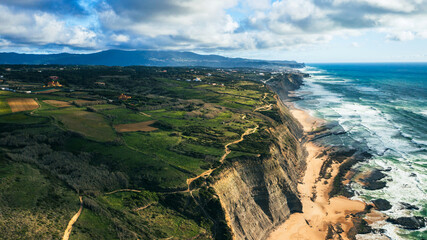 Drone aerial view over long rocky coastline in Magoito with clouds sky over ocean in summer day. Beautiful natural landscape with ocean rocky shore. Drone view over Scenic European tourist destination