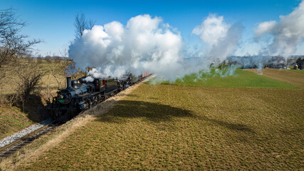 An Aerial View of a Steam Double Header Freight and Passenger Train, Traveling Thru Farmlands, Blowing Smoke, on a Winter Day