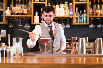 Young mixologist decorating a cocktail glass for customers to consume. Concept: lifestyle, trades, sell