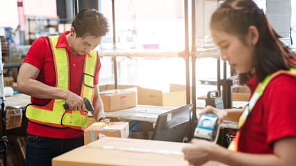 Warehouse worker checking details stock product and scanning a barcode on box package in the...