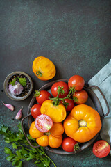 Organic food. Various colorful tomatoes and parsley leaves on a dark stone background. View from above. Copy space.