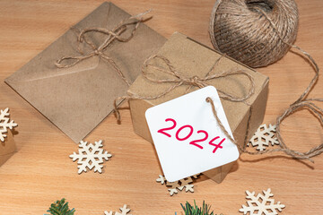 Happy New Year 2024. Gifts made of craft paper with the label 2024 on the table with wooden snowflakes