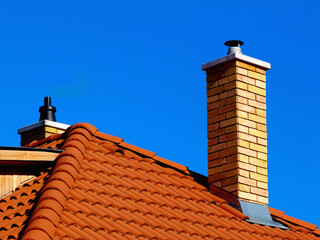 modern brick finished chimneys stack with white concrete cap stone, bright brown red clay roof...
